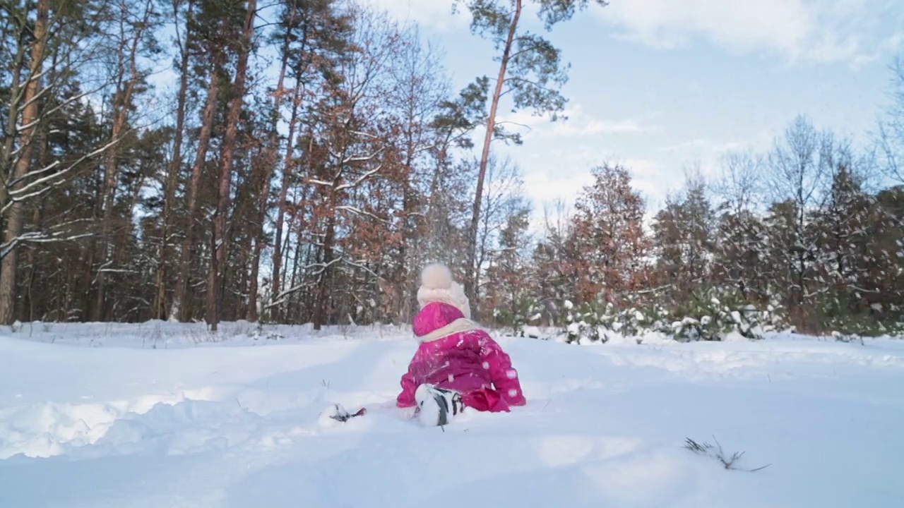 孩子坐在雪堆里玩雪。视频素材