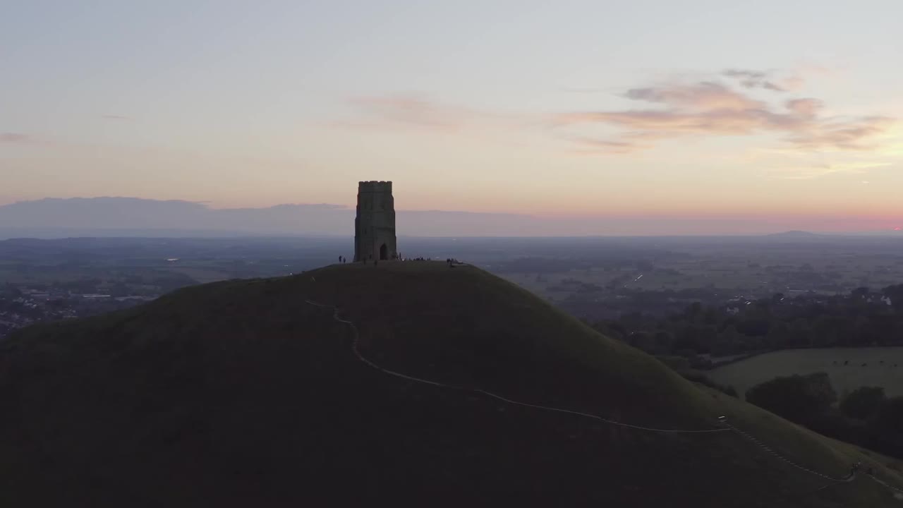 在英国萨默塞特郡，环绕格拉斯顿伯里山的宽阔的日落空中，映衬着乡村和五彩缤纷的天空视频素材