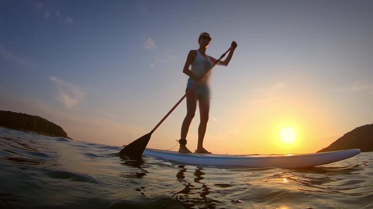 一口冲浪者。日落时，年轻女子在热带海上冲浪视频素材