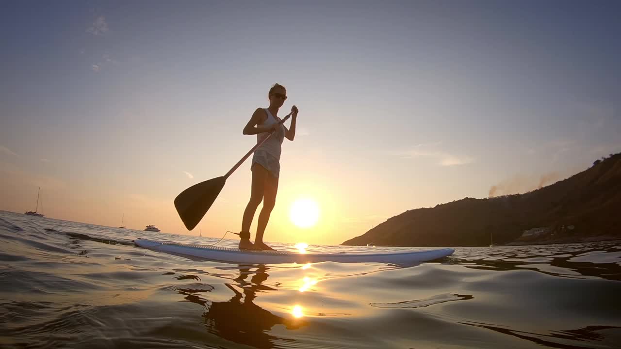 一口冲浪者。日落时，年轻女子在热带海上冲浪视频素材