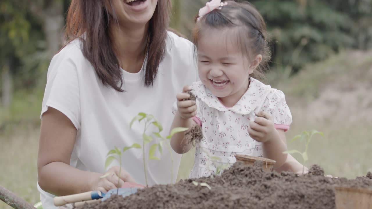 亚洲小女孩和父母有乐趣种植幼苗视频素材