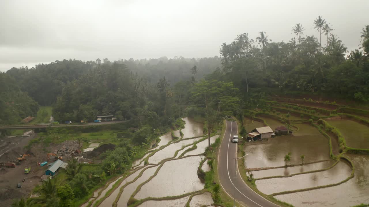 汽车行驶在蜿蜒的道路上，穿过巴厘岛农村的梯田。空中推车拍摄的充满水的稻田在印度尼西亚农村视频素材