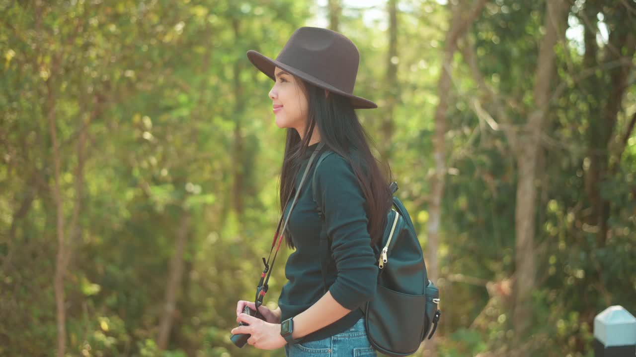 年轻的女人徒步旅行者在森林里用相机拍自然照片，假期和旅游的概念。视频素材