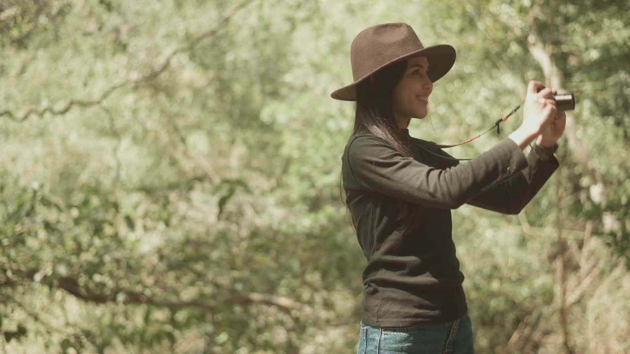 年轻的女人徒步旅行者在森林里用相机拍自然照片，假期和旅游的概念。视频素材