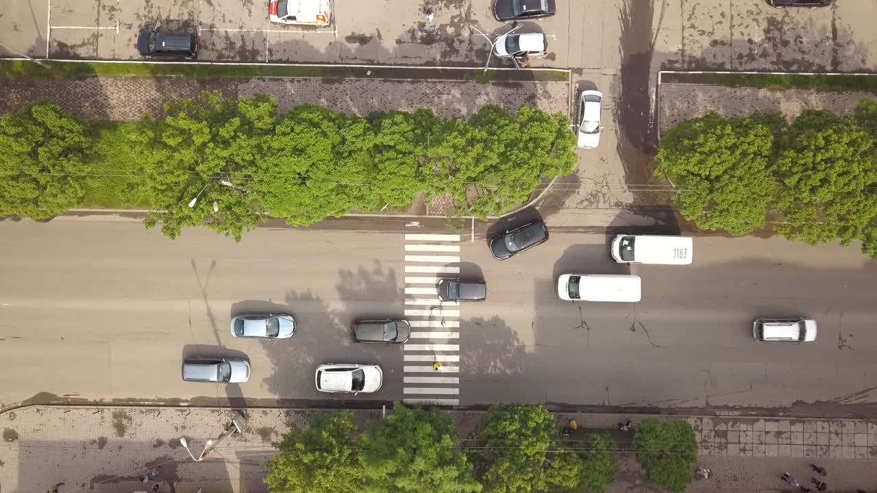 从上到下鸟瞰街道与移动的汽车和斑马线与过街行人。视频素材