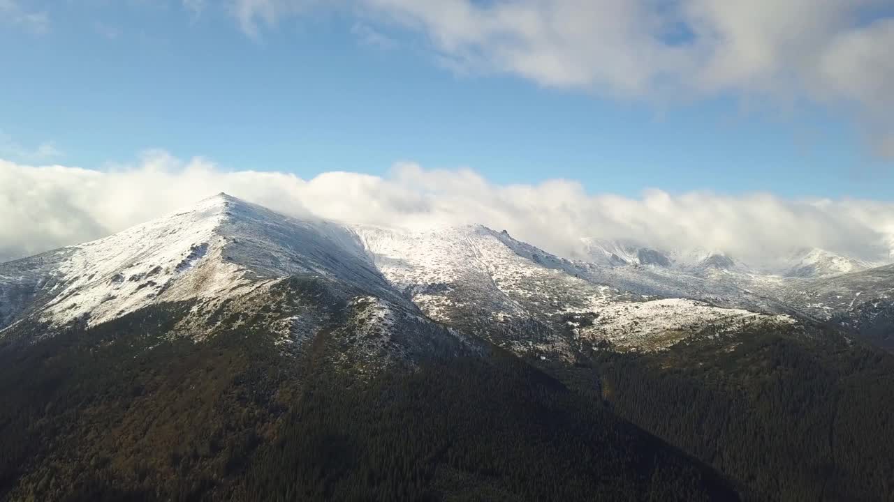 鸟瞰图雄伟的山脉覆盖着绿色云杉森林和高雪峰。视频素材