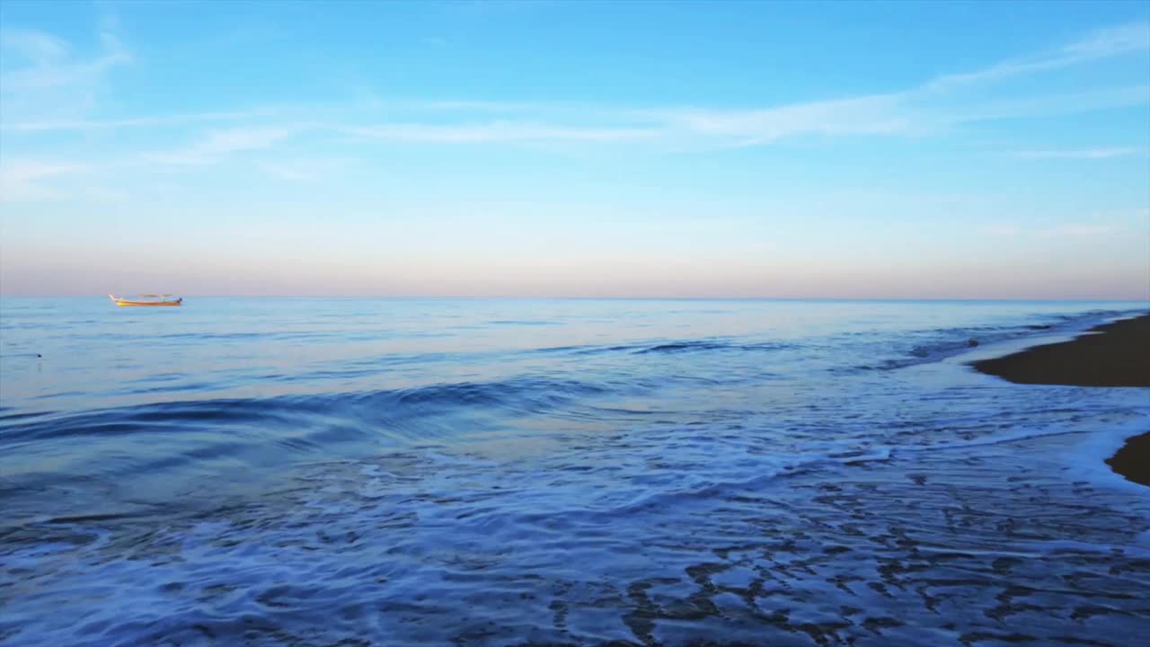 闪亮的金色渐变的海水和平静的海浪撞击着黑暗的夏天海滩视频素材