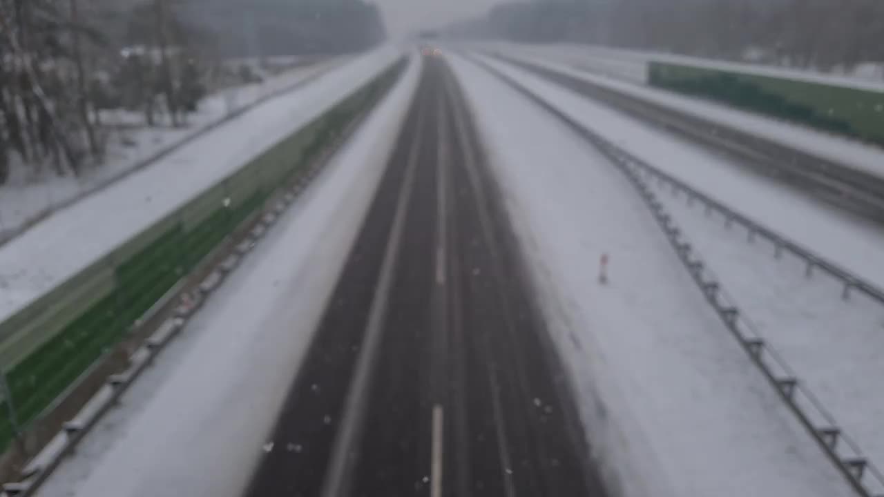 从桥上俯瞰，在暴风雪中高速公路上行驶的汽车视频下载