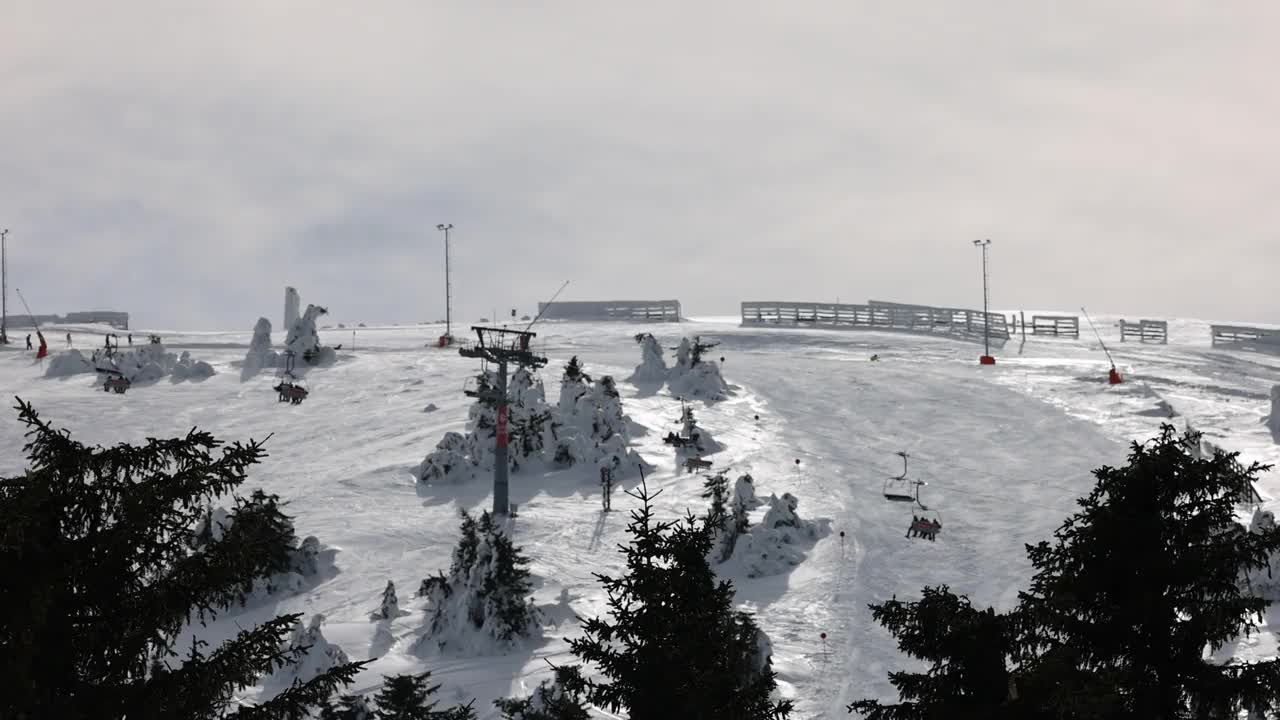 在阴天的冬季，在索道上移动的升降机和在滑雪道上滑雪的滑雪者视频素材