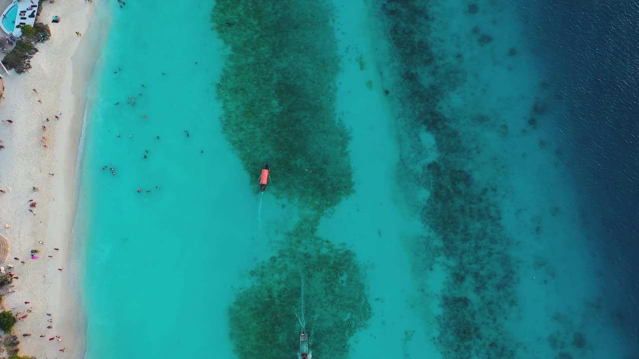 在坦桑尼亚的桑给巴尔岛，从空中俯瞰漂浮在清澈碧绿的海洋上的红色小船视频素材