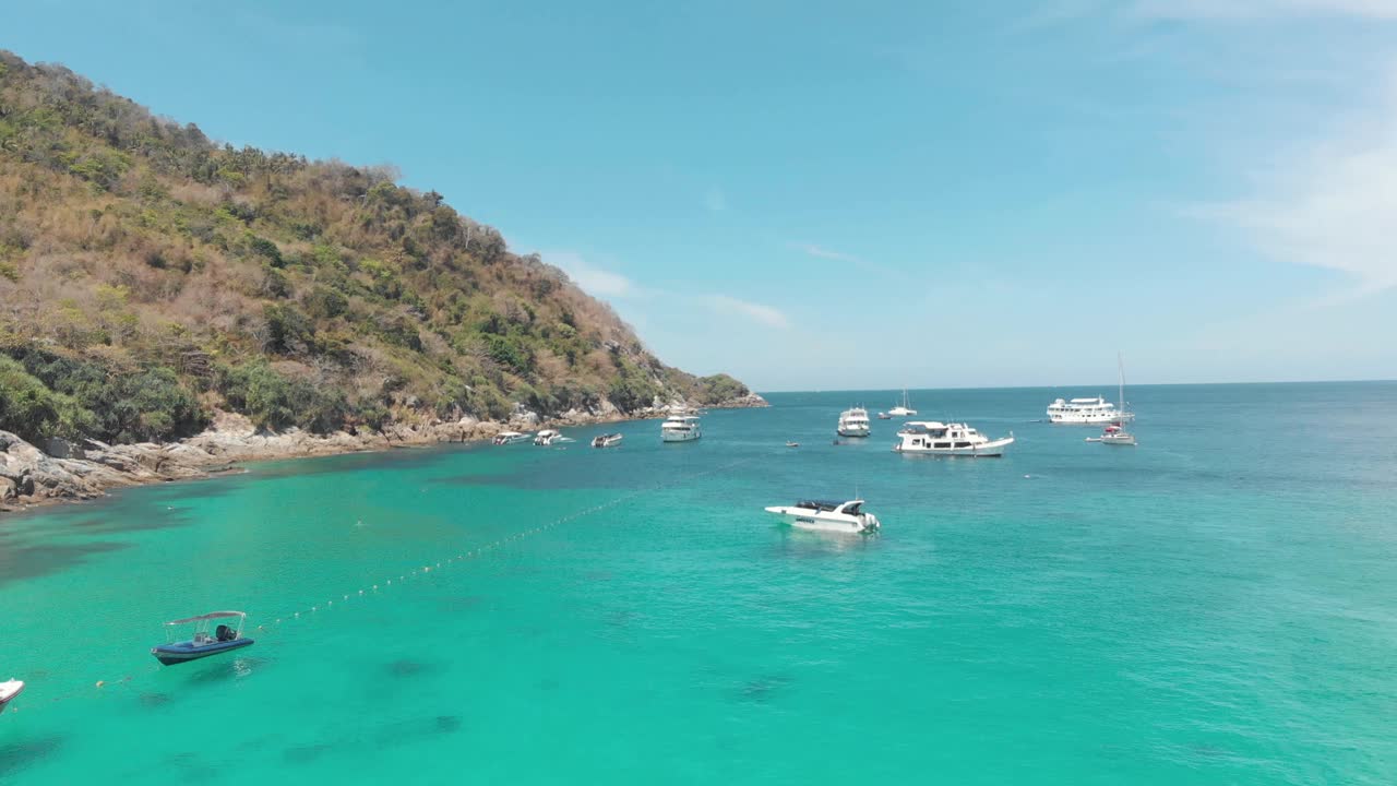 游艇和水晶清澈的蓝色水域周围的陡峭的山毗邻在泰国科拉查耶岛海岸-空中低角度全景拍摄视频素材