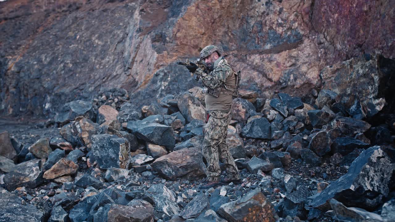 一名全副武装的士兵手持突击步枪在峡谷中移动，这是一次特殊行动。视频素材