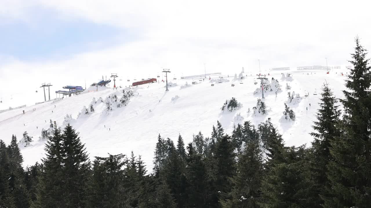 在阳光明媚的冬日，可在索道上升降的升降机及在斜坡上滑雪的滑雪者视频素材