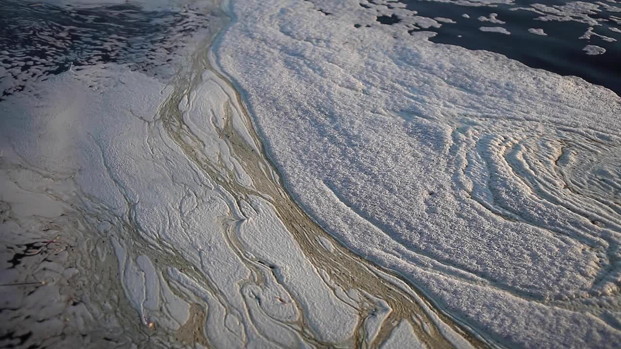 河上的泡沫。脏水在河上泛起涟漪。水污染。视频素材