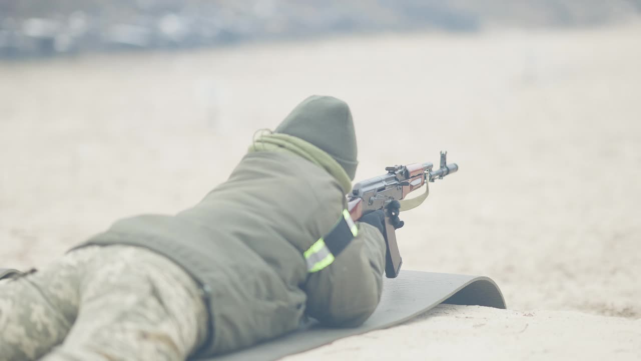 背面的女人躺在多边形射击慢动作从军用枪。自信集中的专业军人在户外多边形训练。视频素材