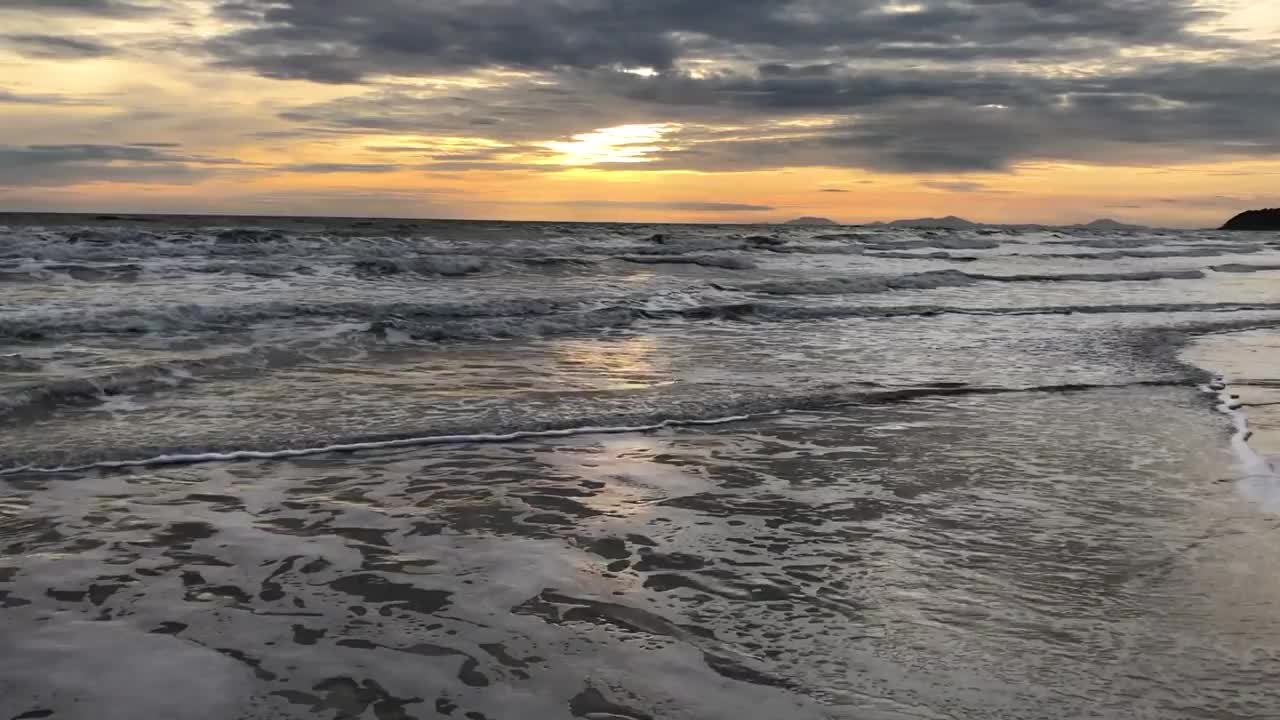 晚上海浪拍打着海滩。海面和海滩上生动的日落天空的反射。色彩斑斓的日出与云在海上，Chanthaburi省，亚洲泰国。视频素材