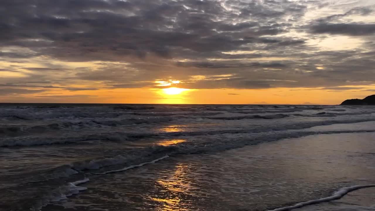 晚上海浪拍打着海滩。海面和海滩上生动的日落天空的反射。色彩斑斓的日出与云在海上，Chanthaburi省，亚洲泰国。视频素材