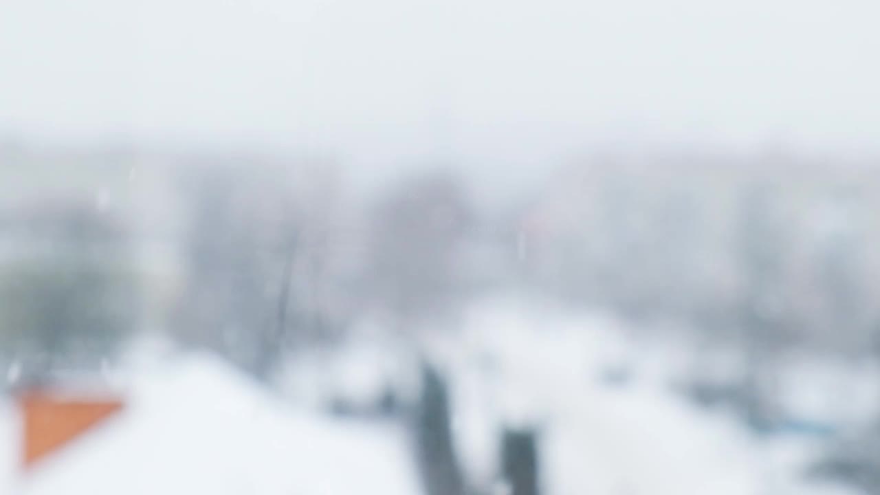 下雪的慢动作。白雪覆盖的城市，雪花飞舞的慢镜头。散焦。有选择性的重点。模糊的冬季背景寒冷的天气视频素材