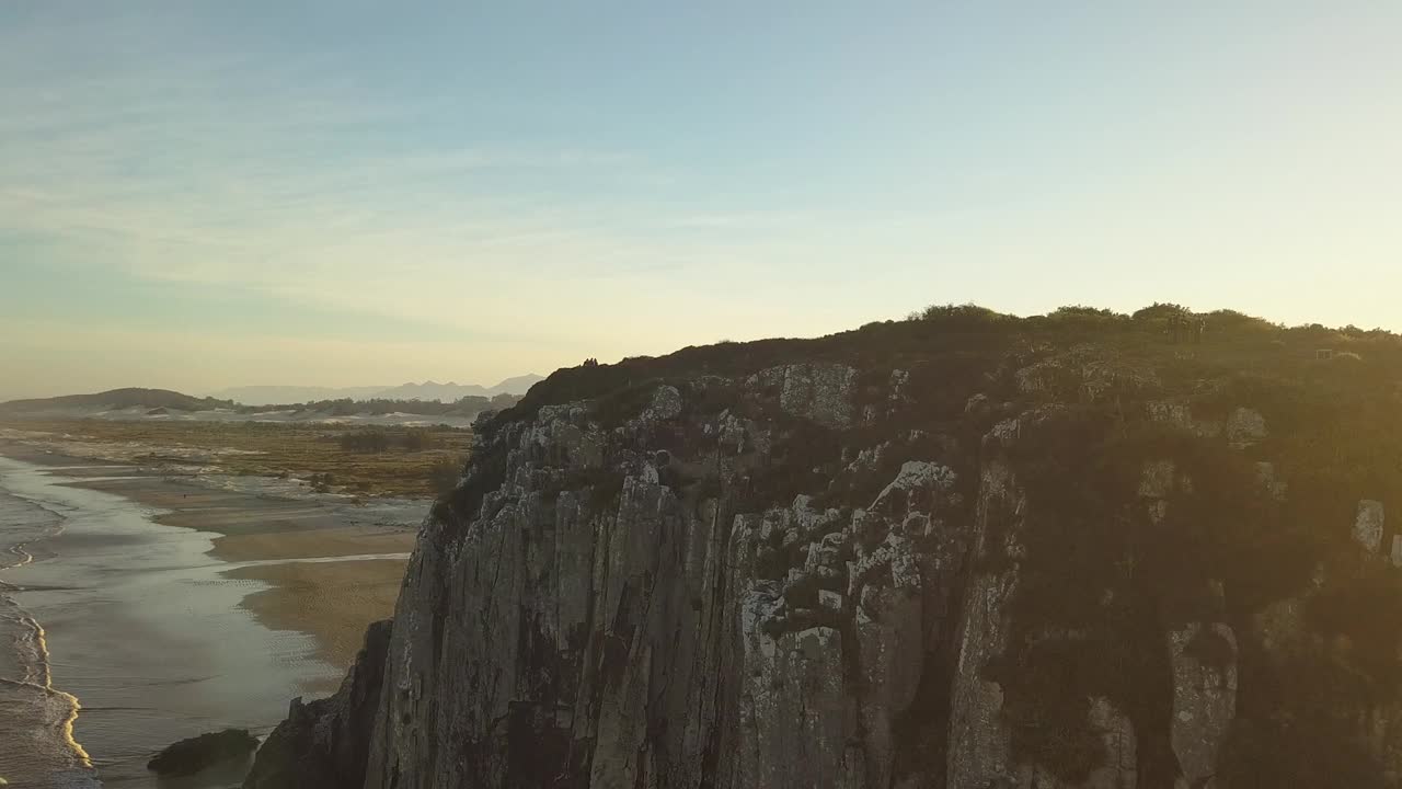 巴西托雷斯瓜里塔海滩黄金时间，在巨大的灰色岩石前空中下降(无人机- 4K)视频素材