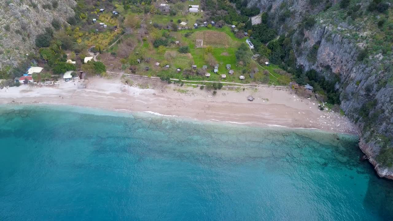 缓慢的空中变焦水晶清澈的蓝色水域幽静的爱琴海海滩蝴蝶谷Mugla土耳其冬季(无人机- 4K)视频下载