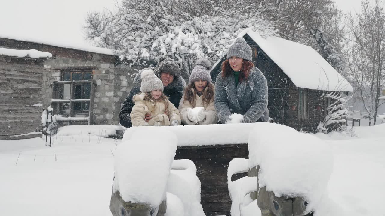 冬季家庭乐趣。把雪。快乐，欢笑，好玩的四口之家正在享受雪和雪，有乐趣，花时间一起在下雪的冬天。慢动作视频素材