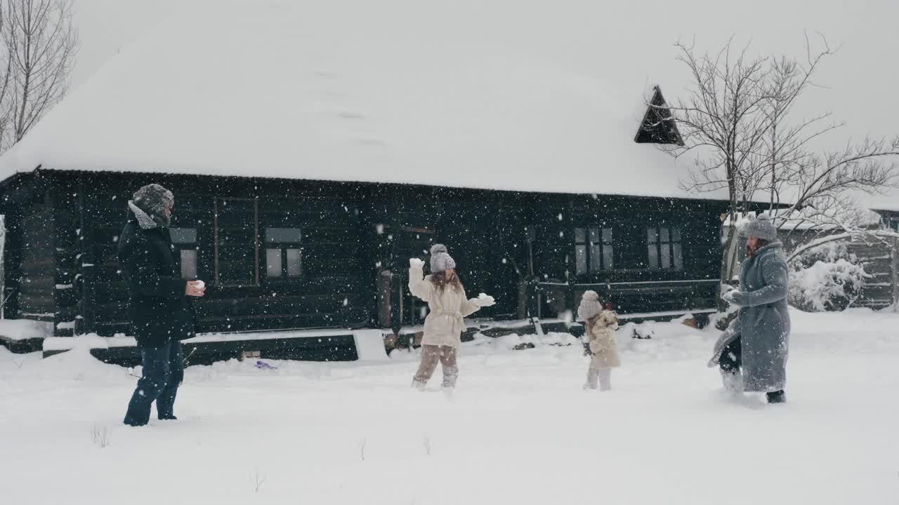 冬季家庭乐趣。扔雪球。快乐的四口之家玩雪，享受雪，在户外玩耍，在下雪的冬天一起度过时光。慢动作视频素材