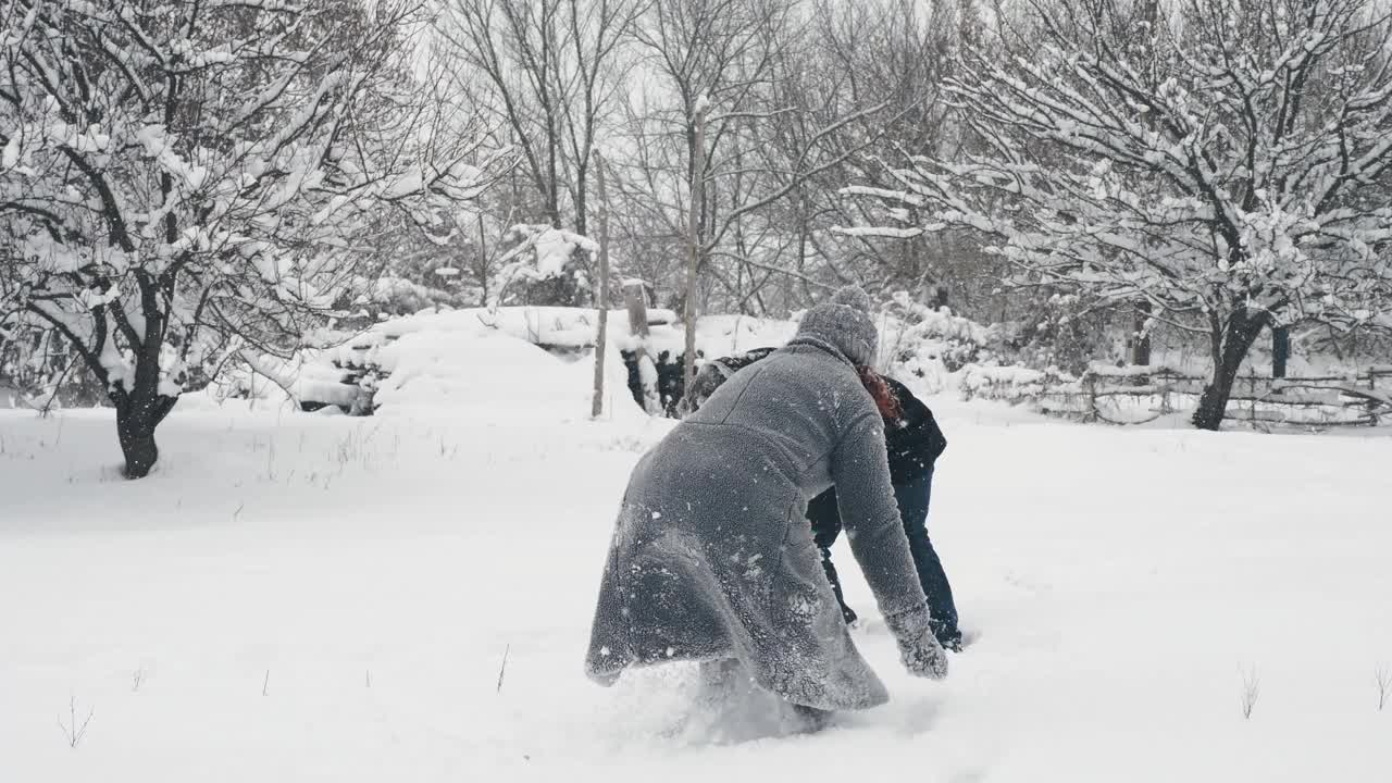 下雪的冬天的乐趣。扔雪球。有趣，幸福的夫妇，男人和女人玩雪球，在户外玩，花时间一起在下雪的冬天。家庭时间。慢动作视频素材