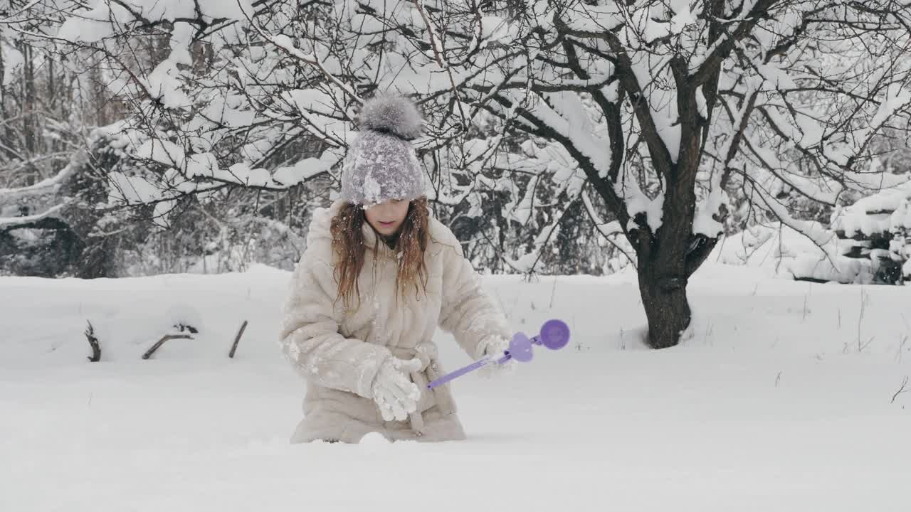 下雪的冬天的乐趣。雪球。快乐的，可爱的，漂亮的女孩，穿着暖和的冬天的衣服，正在做雪球，在户外玩，在下雪的冬天，在公园或森林视频素材