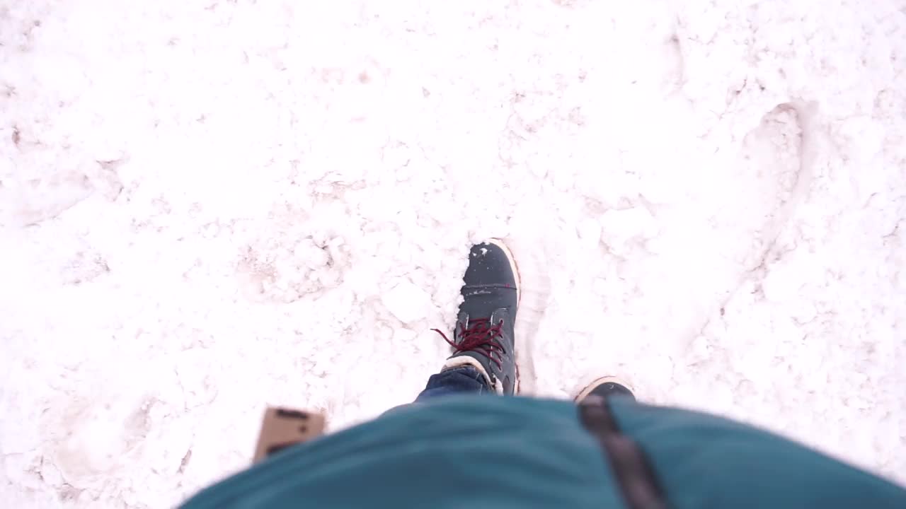 行人在雪地上走路时会打掉鞋上的雪视频素材