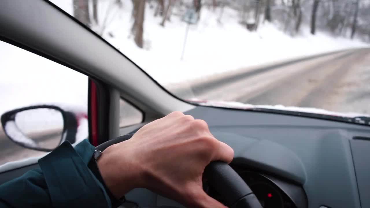 司机用手控制汽车的方向盘在冬天的道路上雪躺在一边视频素材