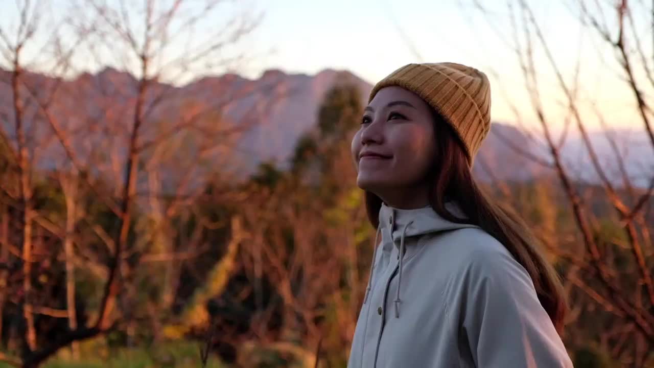 一个女性旅行者站在山顶上看美丽的自然景色的慢动作视频素材