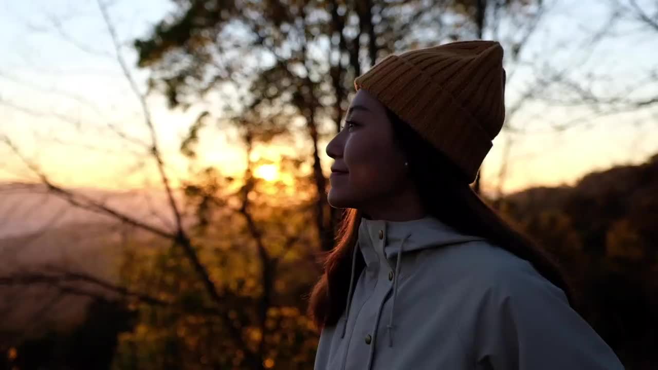 一个女性旅行者站在山顶上看美丽的自然景色的慢动作视频素材