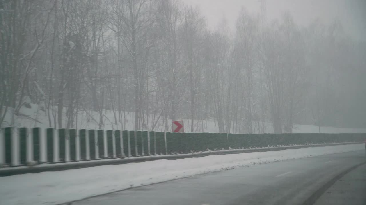 暴风雪期间，汽车在光滑的柏油路上行驶。危险驾驶条件。视频素材