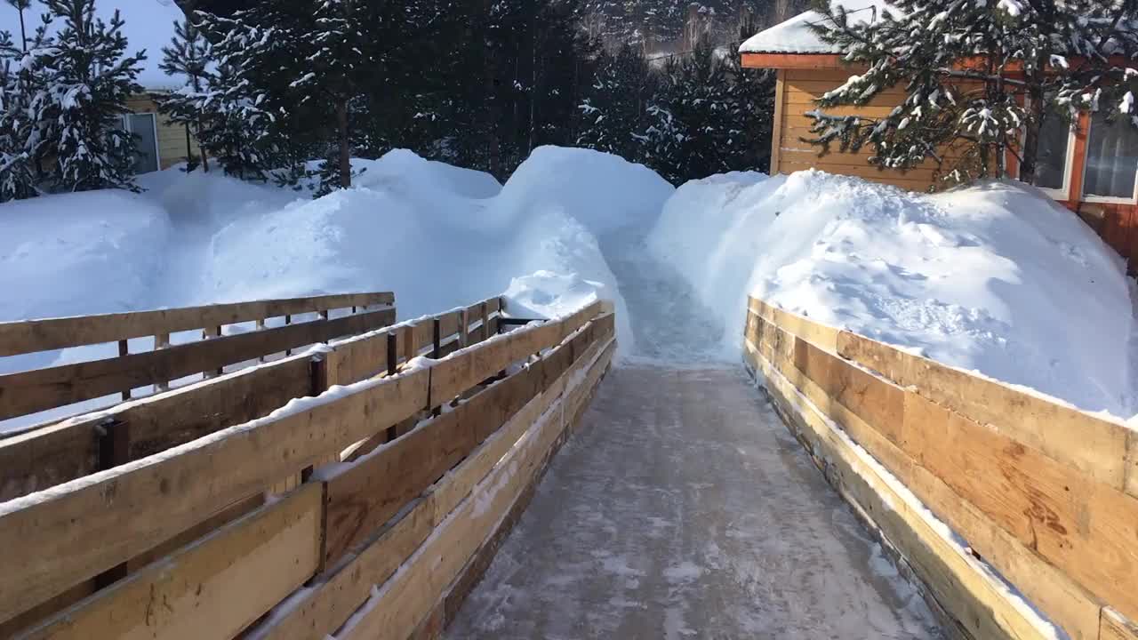 冬天在一个覆盖着雪的木制滑梯上滑雪视频素材