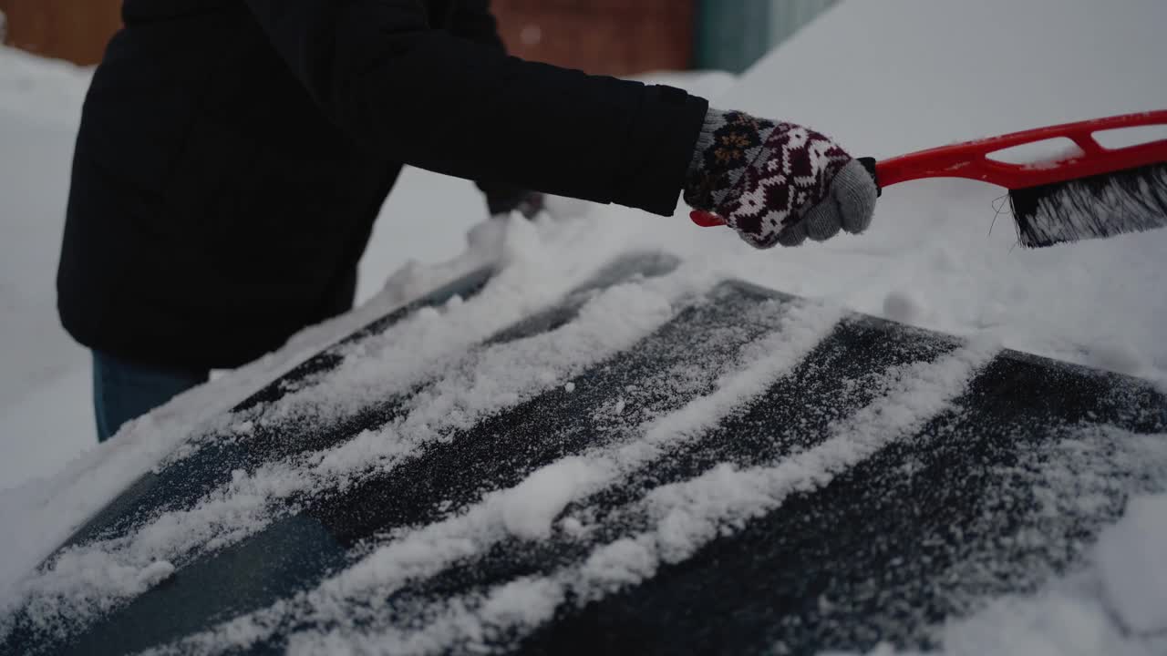 在冬天用刷子清洗汽车罩。男人正在刮车里的雪和冰。大雪覆盖了汽车。关闭了。视频素材