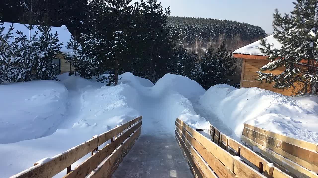 冬天在一个覆盖着雪的木制滑梯上滑雪视频素材