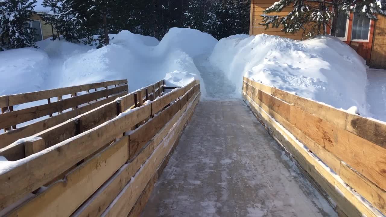 冬天在一个覆盖着雪的木制滑梯上滑雪视频素材