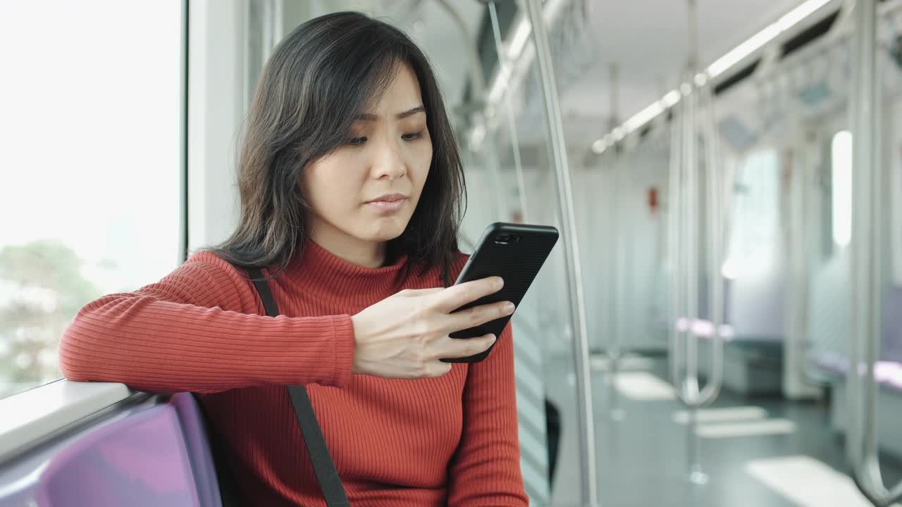 一名年轻女子在地铁上用智能手机视频素材