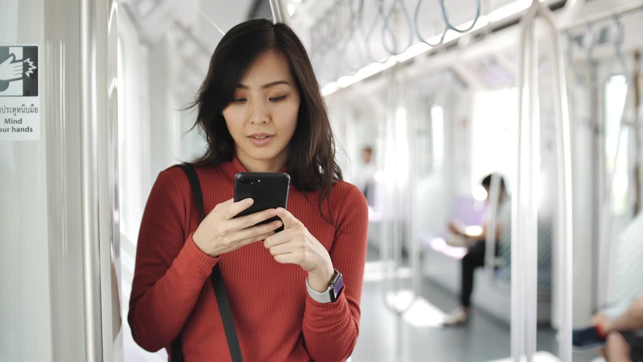 一名年轻女子在地铁上用智能手机视频素材