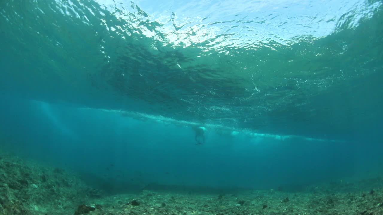 慢动作的男性冲浪者游泳通过海浪海底-南男性环礁，马尔代夫视频素材