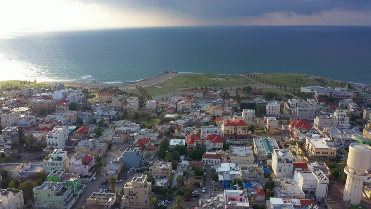 航空拍摄的沿海城市在多云的天空日落，无人机飞向地平线在海上-雅法，以色列视频素材