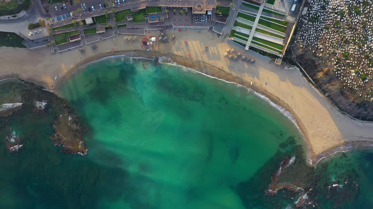 在日落时海浪溅起的空中鸟瞰图，无人机在海岸城市-雅法海滩上空下降，以色列视频素材