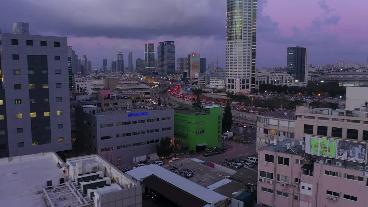 空中拍摄的交通在高速公路在城市的建筑物中，无人机飞向城市景观对多云的天空-特拉维夫，以色列视频素材