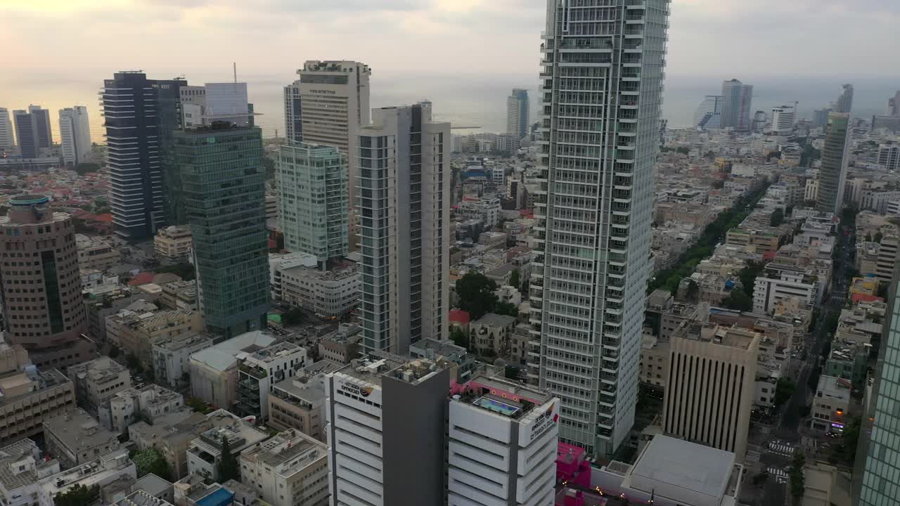 空中平移拍摄的现代建筑在城市市中心的天空，无人机飞过街道上的车辆在日落摩天大楼-特拉维夫，以色列视频素材