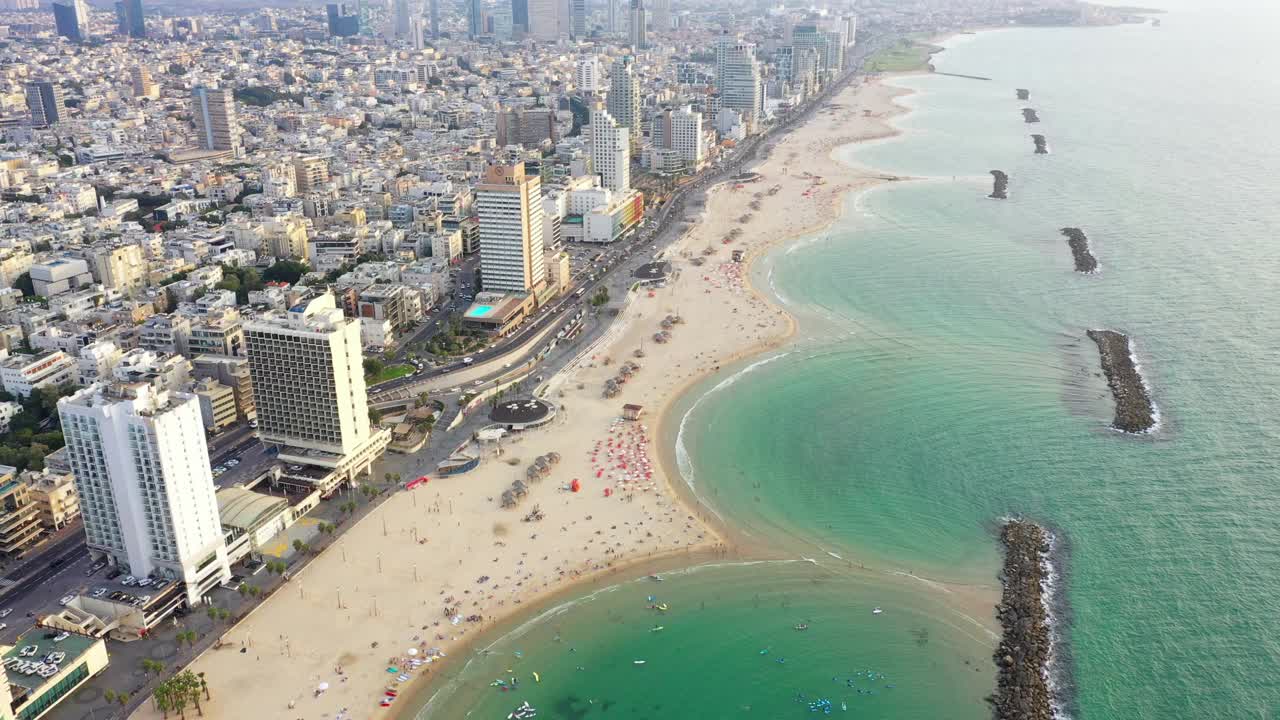 空中拍摄的人们在海滩和Groynes在现代城市，无人机下降在城市景观-特拉维夫，以色列视频素材