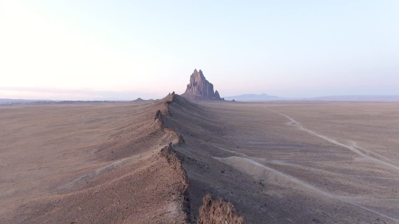 空中缩放在拍摄的岩石山在沙漠的天空，无人机向后飞行在干旱的景观在日落-船泊，新墨西哥视频素材