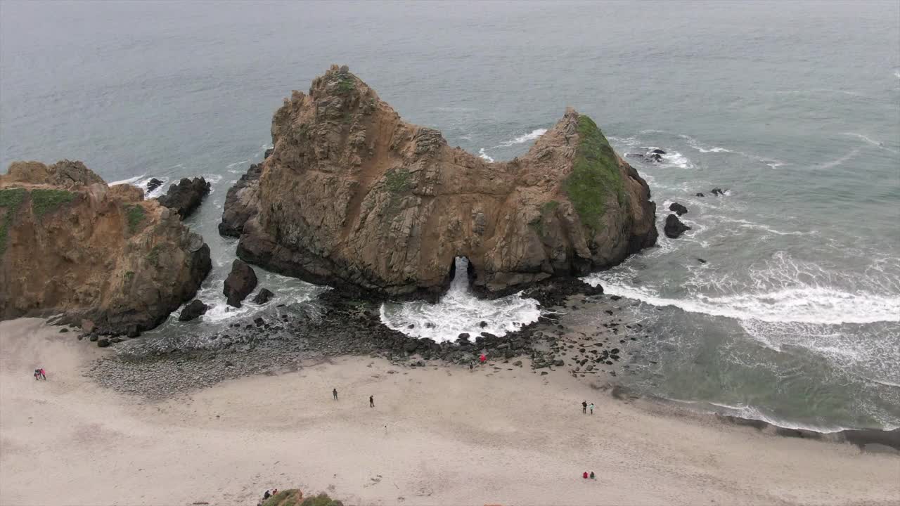 航拍的人在锁眼拱门上，无人机下降前在著名的Pfeiffer海滩溅起海浪-大苏尔，加利福尼亚视频素材