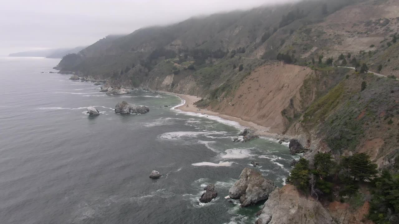 海浪溅在海岸线上的空中拍摄，无人机向后飞行与岩石形成的海滩-大苏尔，加利福尼亚视频素材