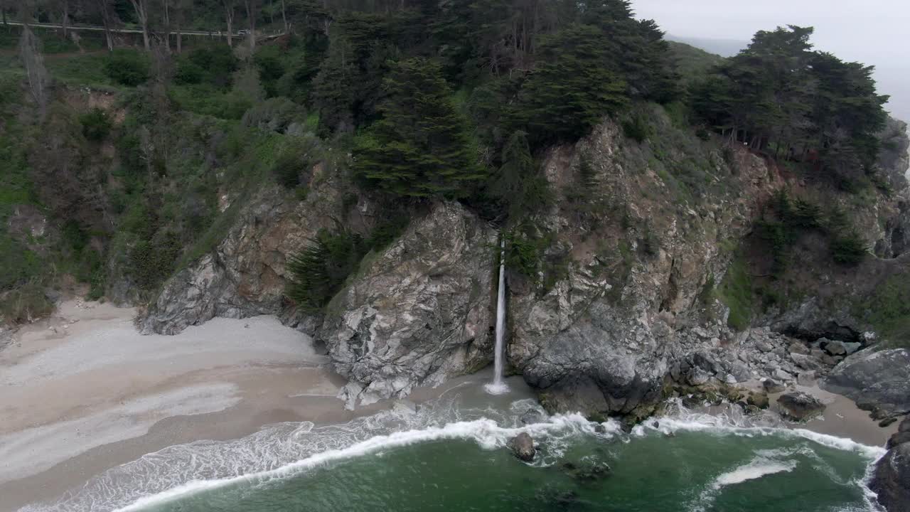 空中摇摄麦克威从海滩的岩石悬崖坠落，无人机飞过浪花溅岸-大苏尔，加利福尼亚视频素材