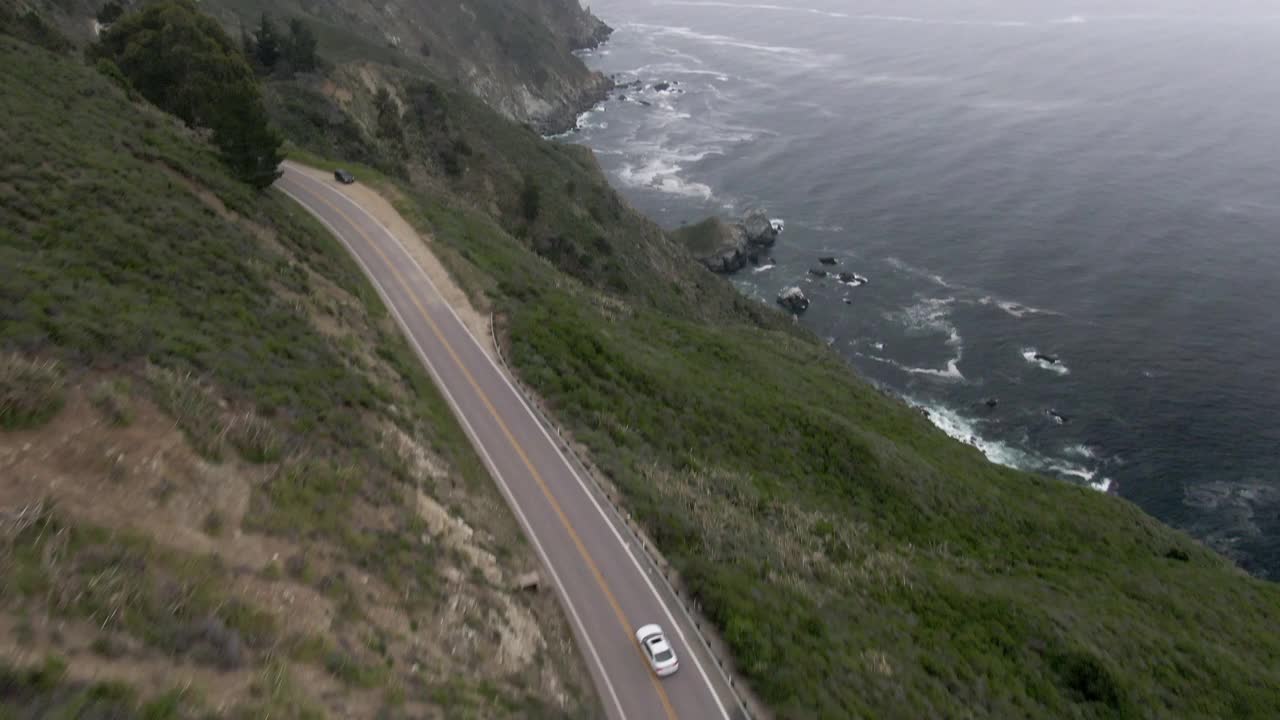 空中倾斜向上拍摄的海岸公路上的山对天空，无人机向前飞行的海岸线-大苏尔，加利福尼亚视频素材